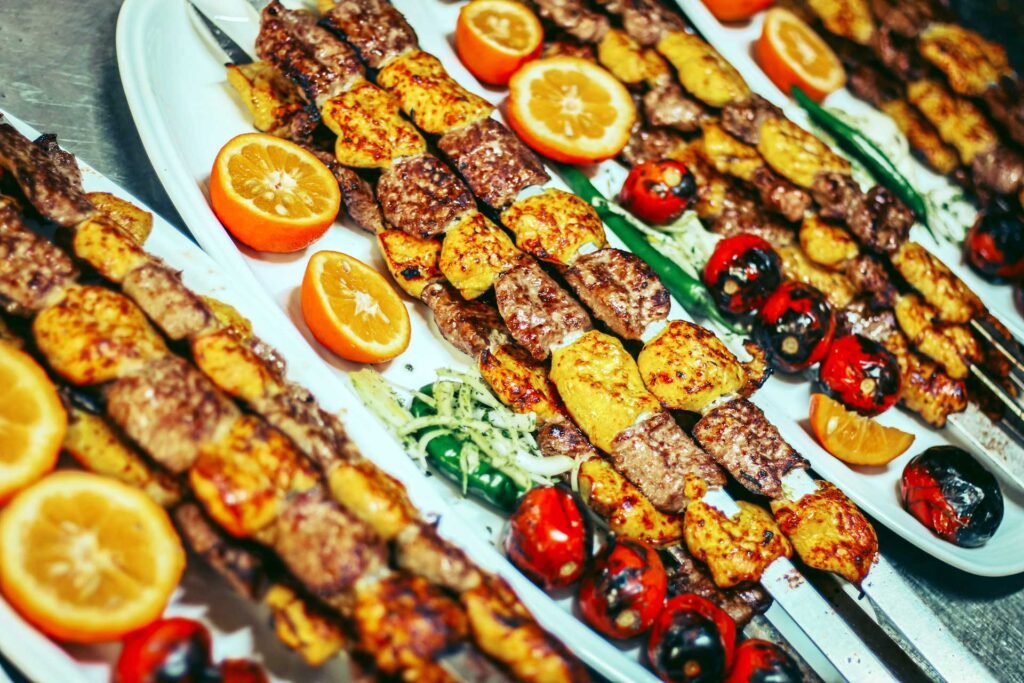 Doner kebab multiple skewers of grilled kebabs, arranged on white plates and garnished with orange slices.