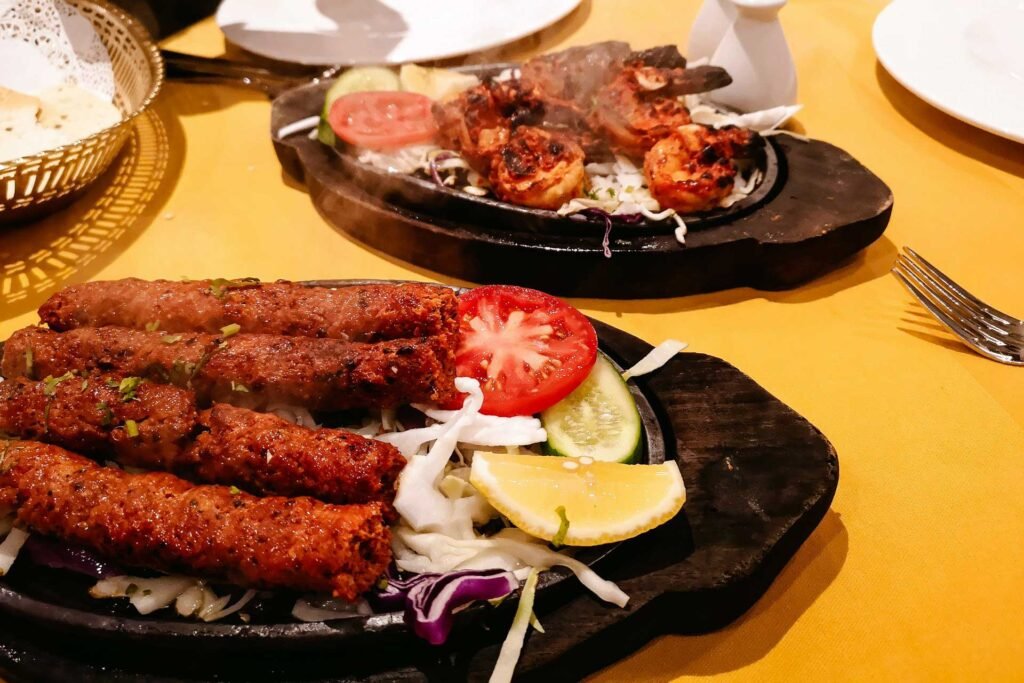 Doner kebab grilled kebabs, garnished with slices of tomatoes, red onion, and lemon.